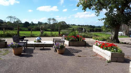 a park with two benches and flowers in pots at Highfields Farm B&B in Stone