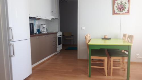 une petite cuisine avec une table et des chaises vertes dans l'établissement Asemantupa 1, à Pyhäsalmi