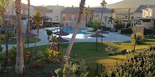 un resort con piscina con ombrelloni e palme di Apartamento Jarales Golf, Atlanterra, Zahara a Zahara de los Atunes