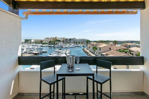 d'une table et de chaises sur un balcon avec vue sur le port. dans l'établissement Village Naturiste R4N - Le Candi Port Venus Panoramic View, au Cap d'Agde