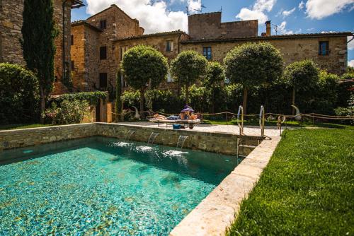 a person sitting on a chair next to a swimming pool at PALAZZO DEL CAPITANO Wellness & Relais - Luxury Borgo Capitano Collection in San Quirico dʼOrcia