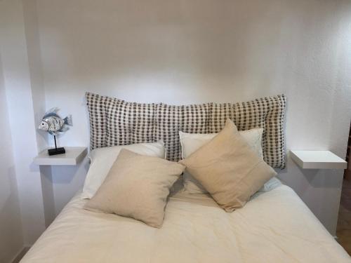 uma cama com quatro almofadas e uma cabeceira em Espectacular apartamento con piscina en Calella de Palafrugell em Calella de Palafrugell