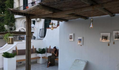 a woman sitting on a bench on a patio at Black Market Hotel in Ischia