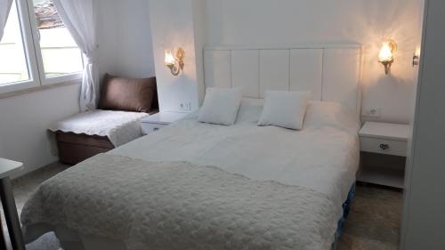 a white bedroom with a large bed and a chair at Apartments Ohrid Lake in Ohrid