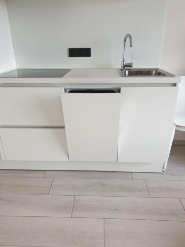 Una cocina con gabinetes blancos y un fregadero. en Appartement, residentie Syci, en Koksijde