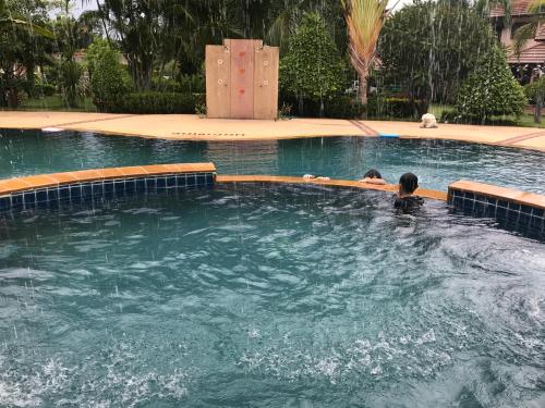 two people are swimming in a swimming pool at Papai Country Lodge SHA in Ban Mae Pong