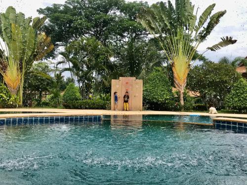 two people standing in front of a swimming pool at Papai Country Lodge SHA in Ban Mae Pong