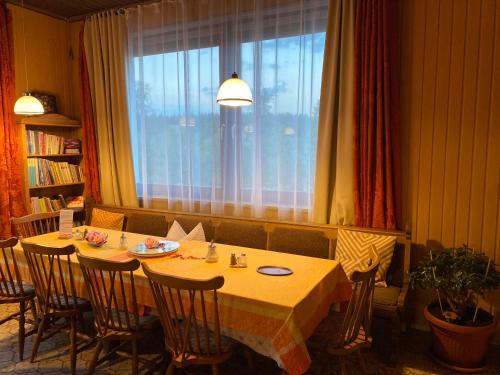 a dining room with a table with chairs and a window at Pension Waldblick in Spiegelau
