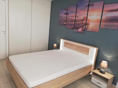 - une chambre avec un grand lit blanc orné de peintures murales dans l'établissement Appartement 2P et parking privé à 50m des plages., à Villeneuve-Loubet