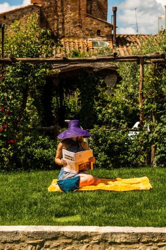 a woman sitting in the grass reading a book at PALAZZO DEL CAPITANO Wellness & Relais - Luxury Borgo Capitano Collection in San Quirico dʼOrcia