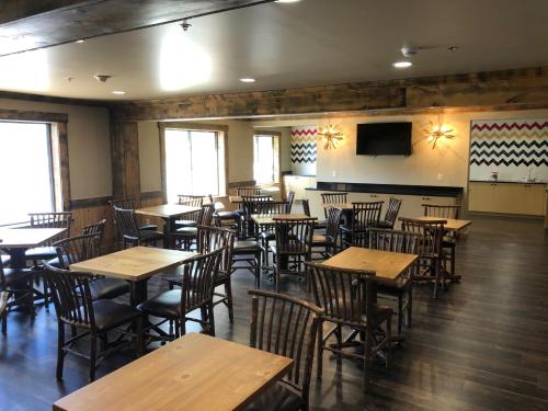 a restaurant with wooden tables and chairs and a flat screen tv at Clubhouse Inn in West Yellowstone