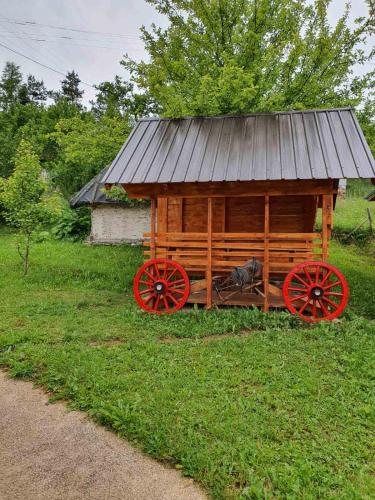 a wooden cabin with red wagon wheels in a field at Vila Medo in Brdo