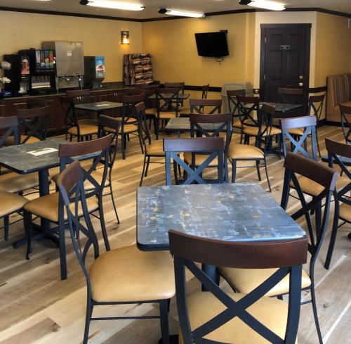 a dining room with tables and chairs and a tv at Yellowstone West Gate Hotel in West Yellowstone