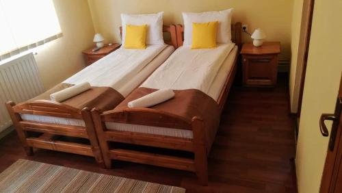 two twin beds in a small room with yellow pillows at Levi Panzio in Praid
