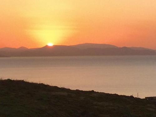 a sunset over the water with mountains in the background at Villa Aqua Marina in Vourkarion