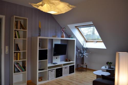a living room with a white book shelf with a tv at Ferienwohnung An der Försterei in Öhrenfeld