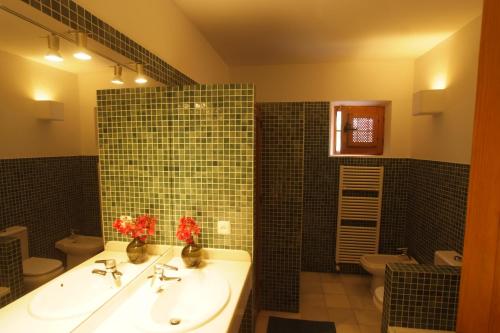 ein Badezimmer mit zwei Waschbecken und einer grünen Wand mit Fliesenböden in der Unterkunft Casa el Arenal in Níjar