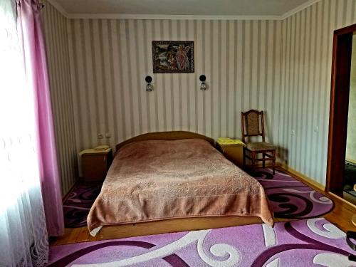 a bedroom with a bed and a chair and a rug at Садиба Святослав in Skhidnitsa