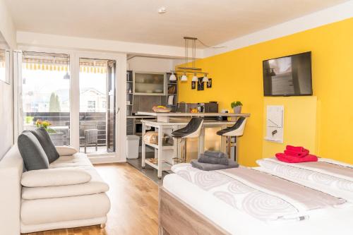a living room with two white couches and a yellow wall at Ein Zimmer Apartment Bernau mit großer Garage incl in Bernau am Chiemsee