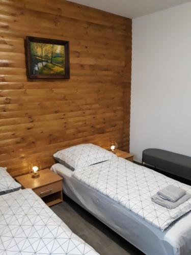 two beds in a room with wooden walls at Agroturystyka Pod Dębami in Bolesławiec