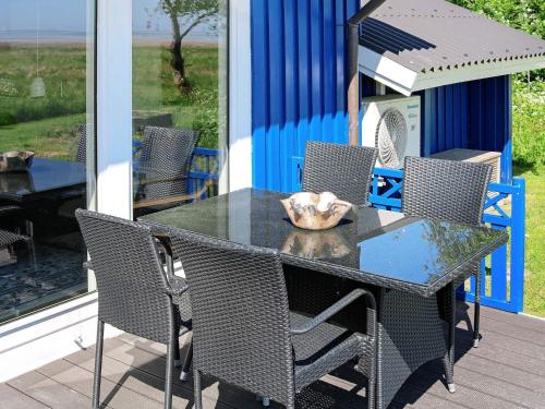 Helberskovにある8 person holiday home in Hadsundのガラスのテーブルと椅子が備わるパティオ