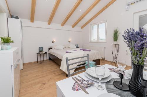 ein weißes Zimmer mit einem Bett und einem Tisch mit Weingläsern in der Unterkunft Studio Apartment Harmony NP Krka in Lozovac