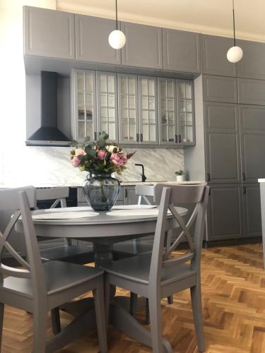 a kitchen with a table with a vase of flowers on it at Nightingale apartment in Liepāja