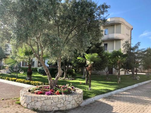 a tree in a flower bed in front of a building at Hotel Autostrada (Highway) in Kashari