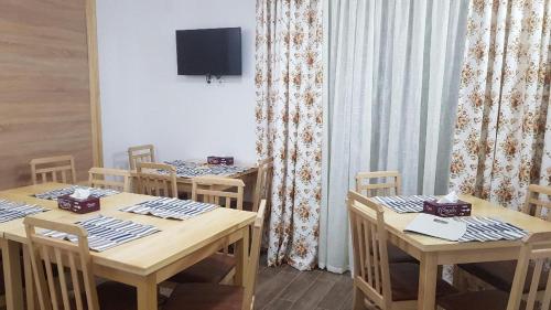 a dining room with two tables with chairs and a tv at PENSIUNEA BERCA in Berca