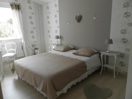 a bedroom with a bed and two chairs and a window at Au pré du Mignon aux portes du Marais Poitevin in Thorigny