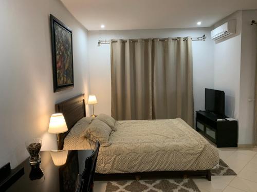 a bedroom with a bed and a television in it at Au Cœur Des Plages de Rabat in Oulad Kerroum