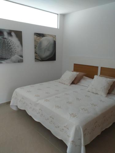 a bedroom with a white bed with two pictures on the wall at Casa Kristin (WLAN gratis) in Costa Calma