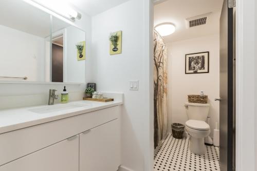 La salle de bains blanche est pourvue d'un lavabo et de toilettes. dans l'établissement Luxury 1BR OLD CITY-KING BED Walk to Liberty Bell & Independence Mall - FREE PARKING!, à Philadelphie