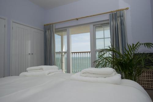 two beds in a room with a view of the ocean at The Vitamin Sea in Ventnor