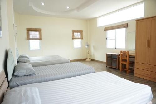 une chambre d'hôtel avec deux lits et un bureau ainsi qu'une chambre dans l'établissement Oriental Beach By Winnie, à Cha Am