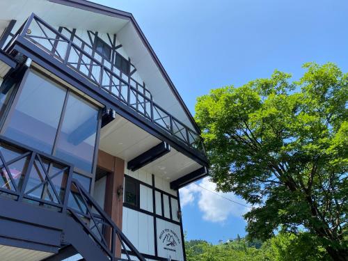 a building with a balcony and a tree at Belle Vue Nishiura in Minami Uonuma
