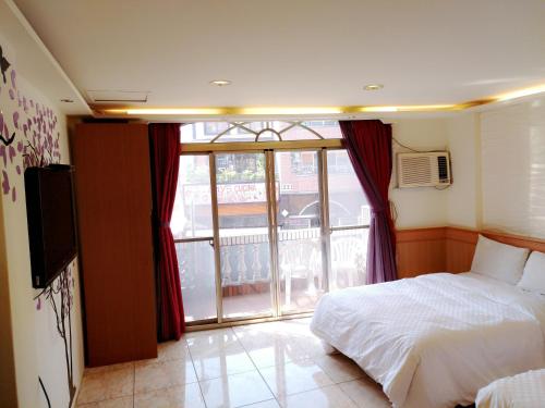 1 dormitorio con 1 cama, TV y ventana en Hong Ben Hotel, en Kenting