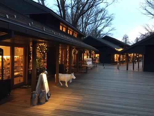 a cow standing on a boardwalk in front of a store at Angel Resort Karuizawa in Karuizawa