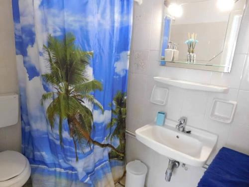 a bathroom with a sink and a shower curtain with a palm tree at Yacht front apartment - Νο 2 in Ios Chora