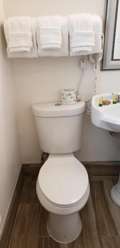 a bathroom with a toilet and a sink and towels at The Palomar Inn in Pismo Beach