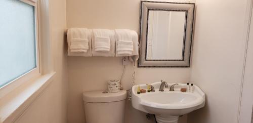 a bathroom with a sink and a toilet and a mirror at The Palomar Inn in Pismo Beach