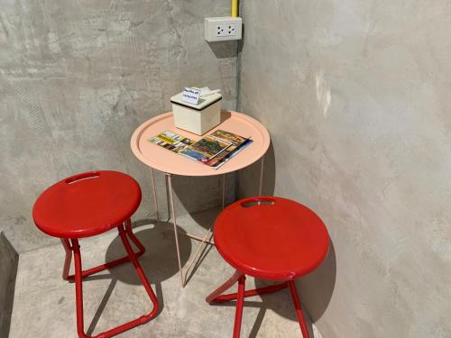 a table with two red chairs and a box on it at BeachBox@Koh Сhang in Ko Chang