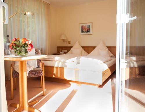 バーデンヴァイラーにあるHotel Morgensonneのベッド2台、テーブル(花付)が備わる客室です。