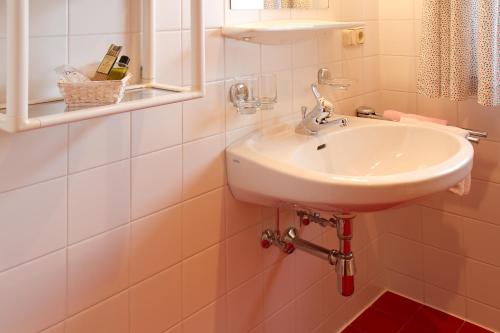 Baño blanco con lavabo y espejo en Ferienhaus Aurora, en Kals am Großglockner
