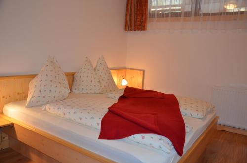 a bedroom with a bed with a red blanket on it at Pension zum Schreiner in Hermagor