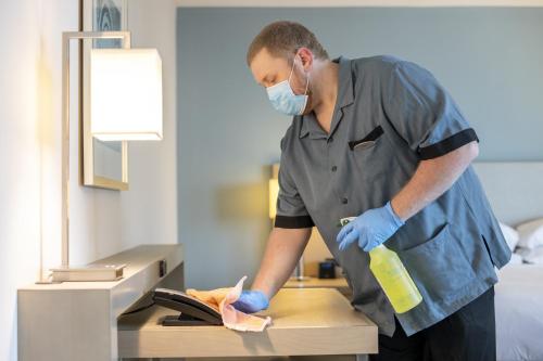 a man wearing a mask and blue gloves is cleaning a counter at Hyatt House Santa Clara in Santa Clara