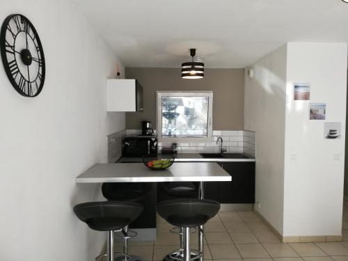 une cuisine avec trois tabourets de bar et une horloge sur le mur dans l'établissement Appartement 2P et parking privé à 50m des plages., à Villeneuve-Loubet