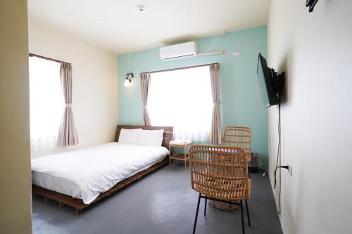 a bedroom with a bed and two windows and a chair at Adan hotel in Nago