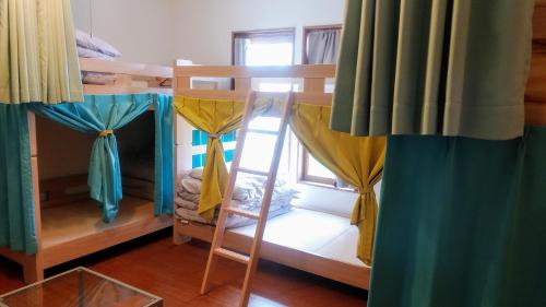 日光市にある奥日光ゲストハウスJUNのベッドルーム1室(カーテン付きの二段ベッド、窓付)