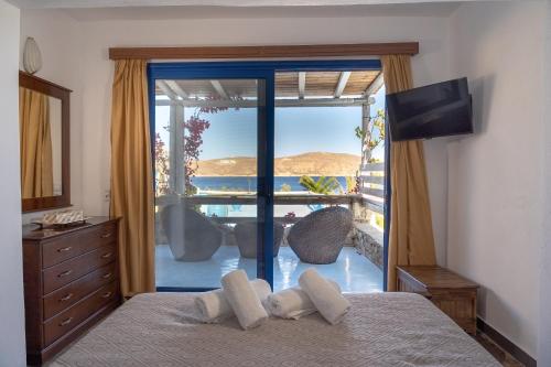 a bedroom with a bed with a view of the ocean at Alexandros by the Beach - Serifos in Livadakia